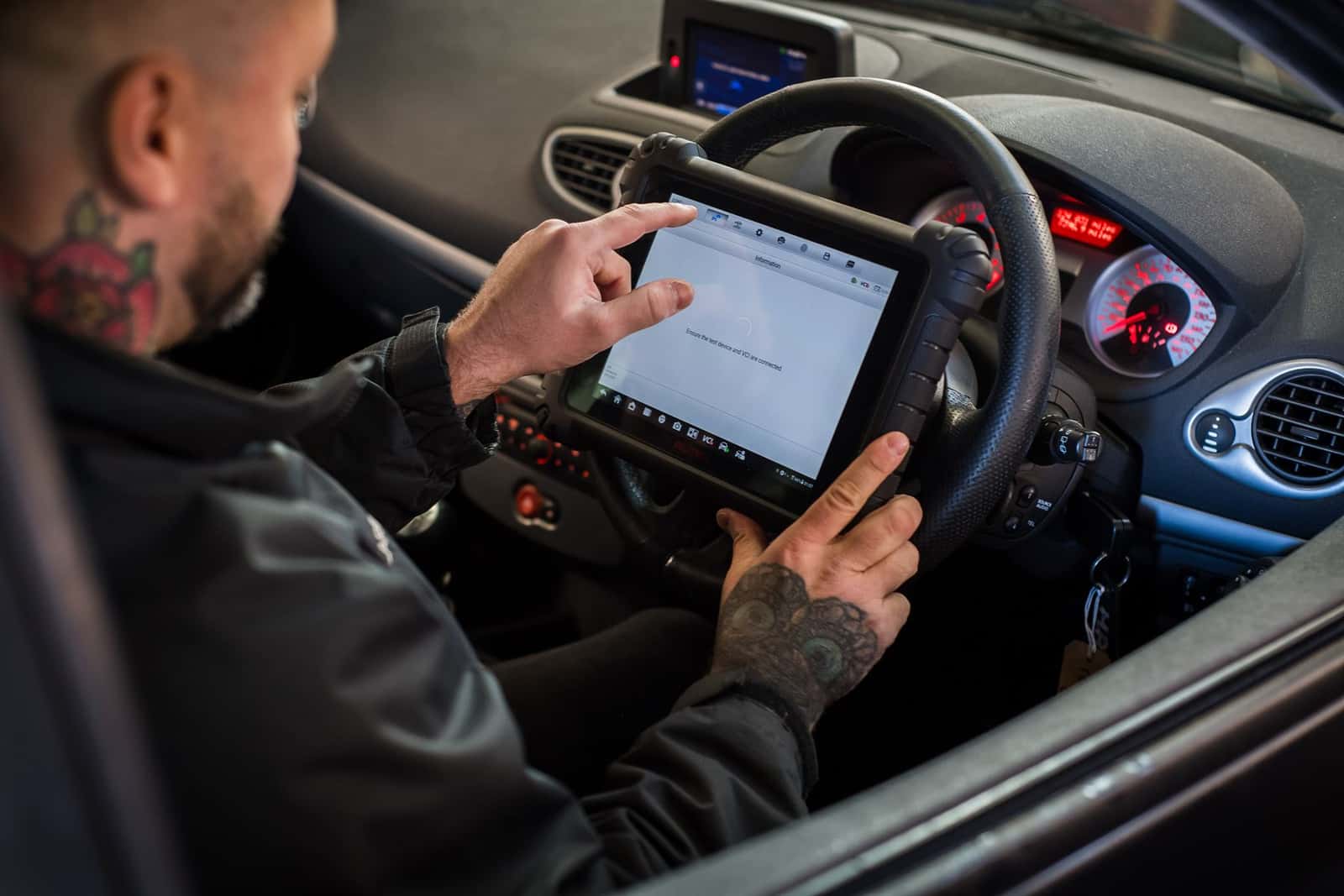 A technician using a diagnostic tablet inside a car
