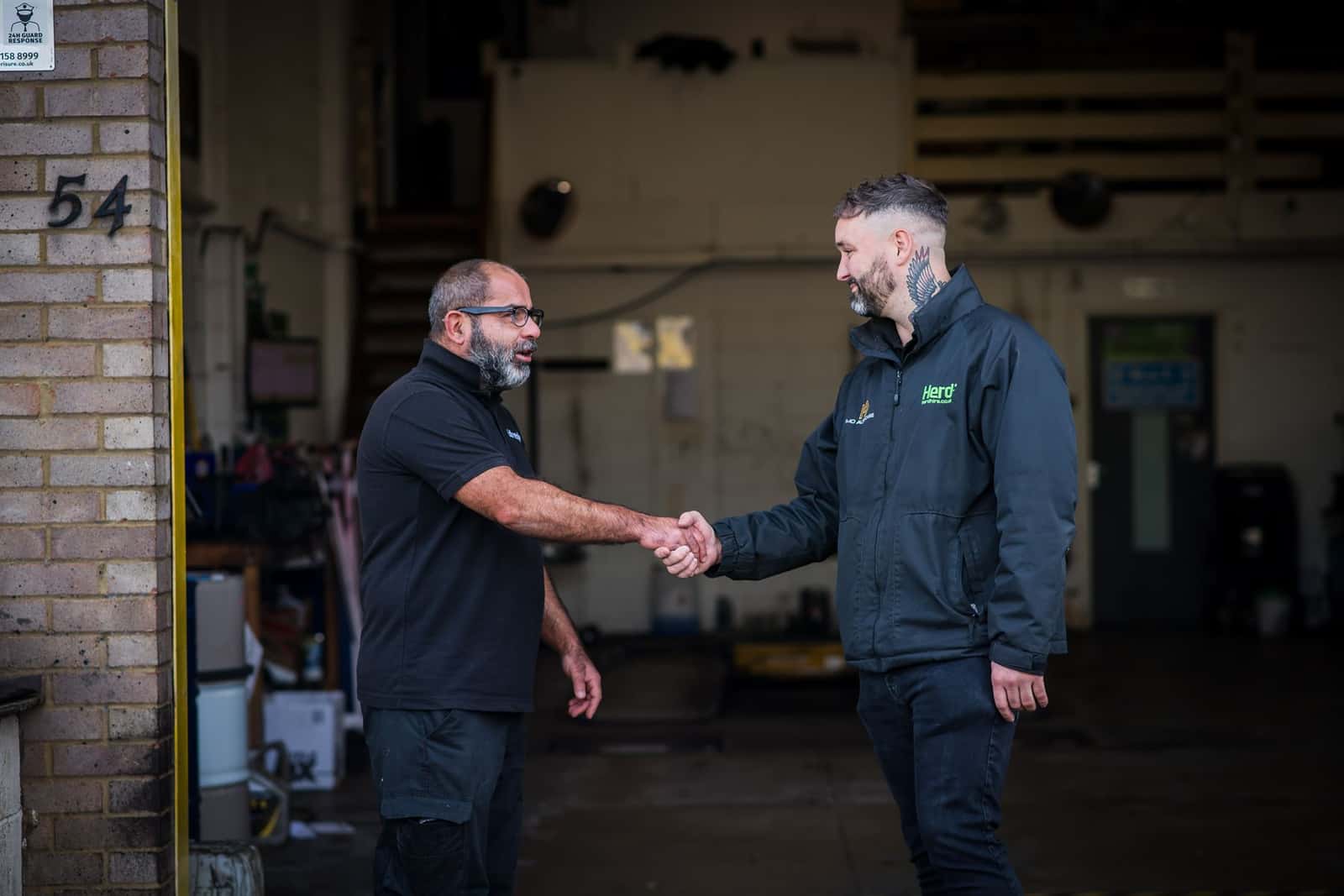 Two members of the M D Auto Care team shaking hands at the garage entrance