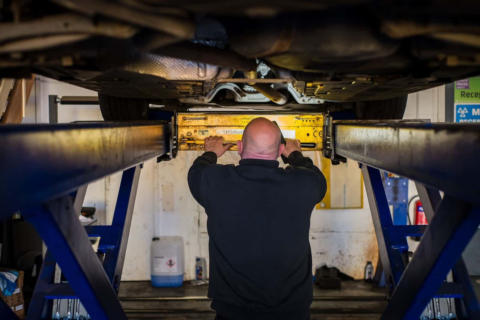 A technician checking the underbody of a car on a lift