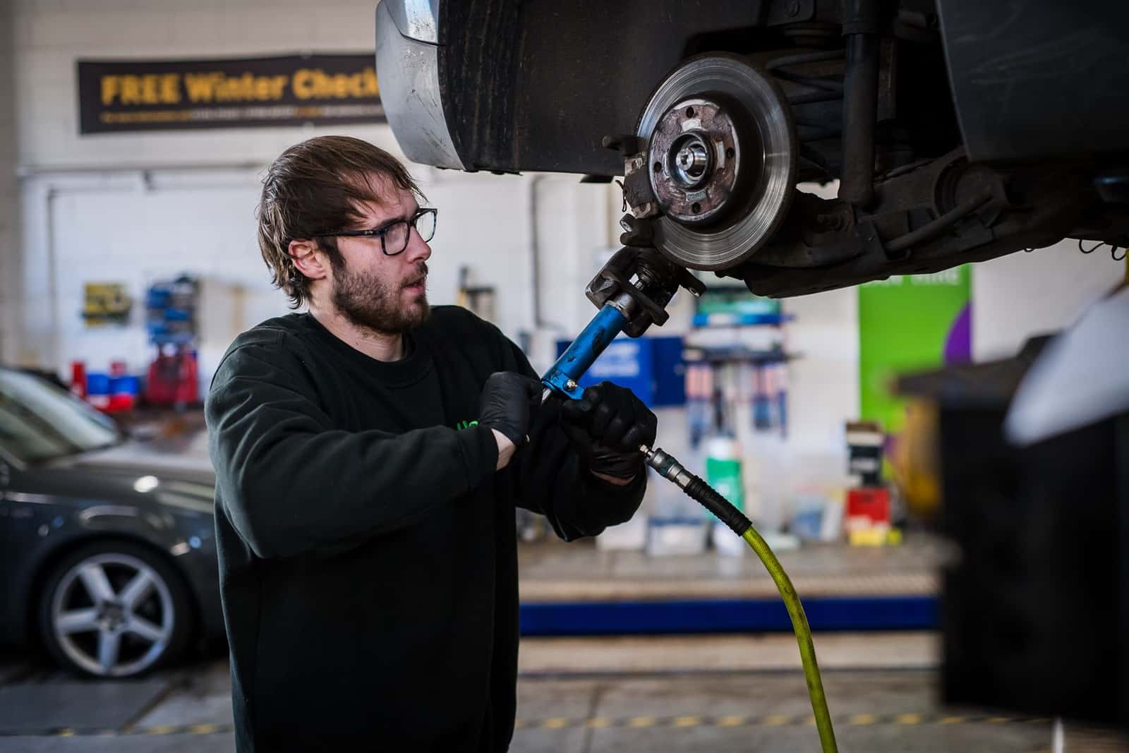A technician working on a car's brake disc and wheel hub